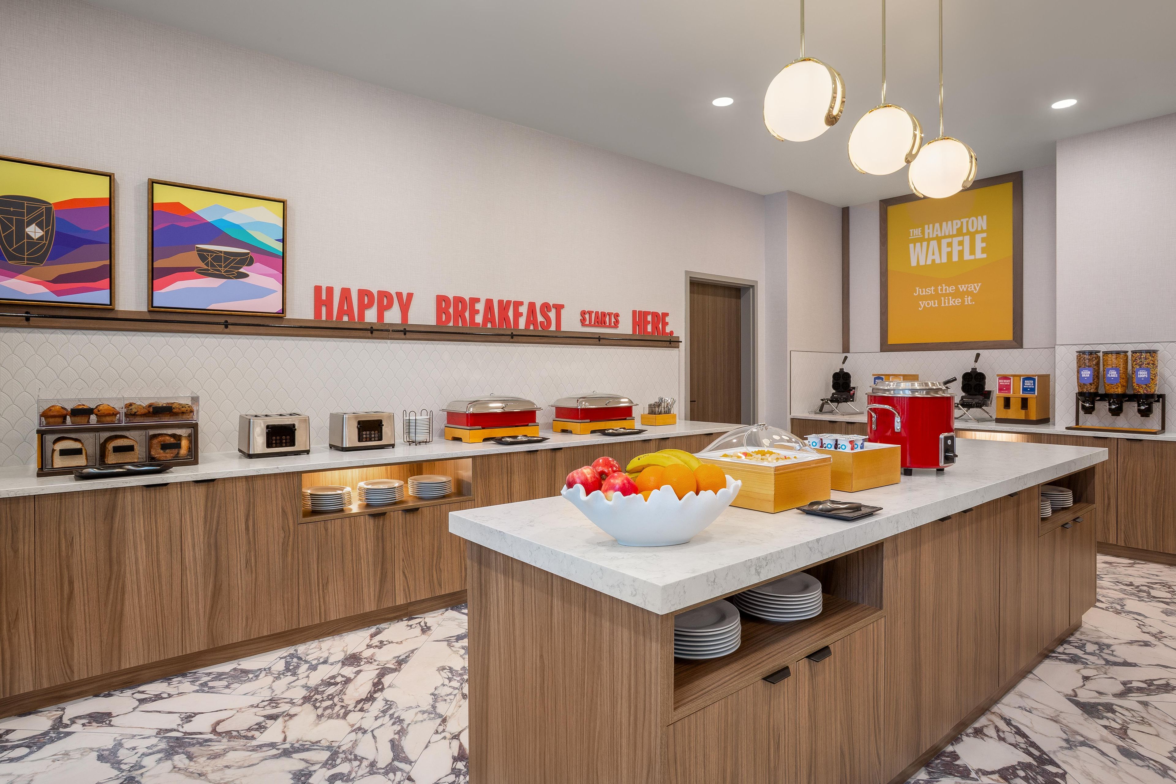 Ein Frühstücksbuffet mit einer Auswahl an Speisen und einem Schild mit der Aufschrift 'HAPPY BREAKFAST STARTS HERE'.
