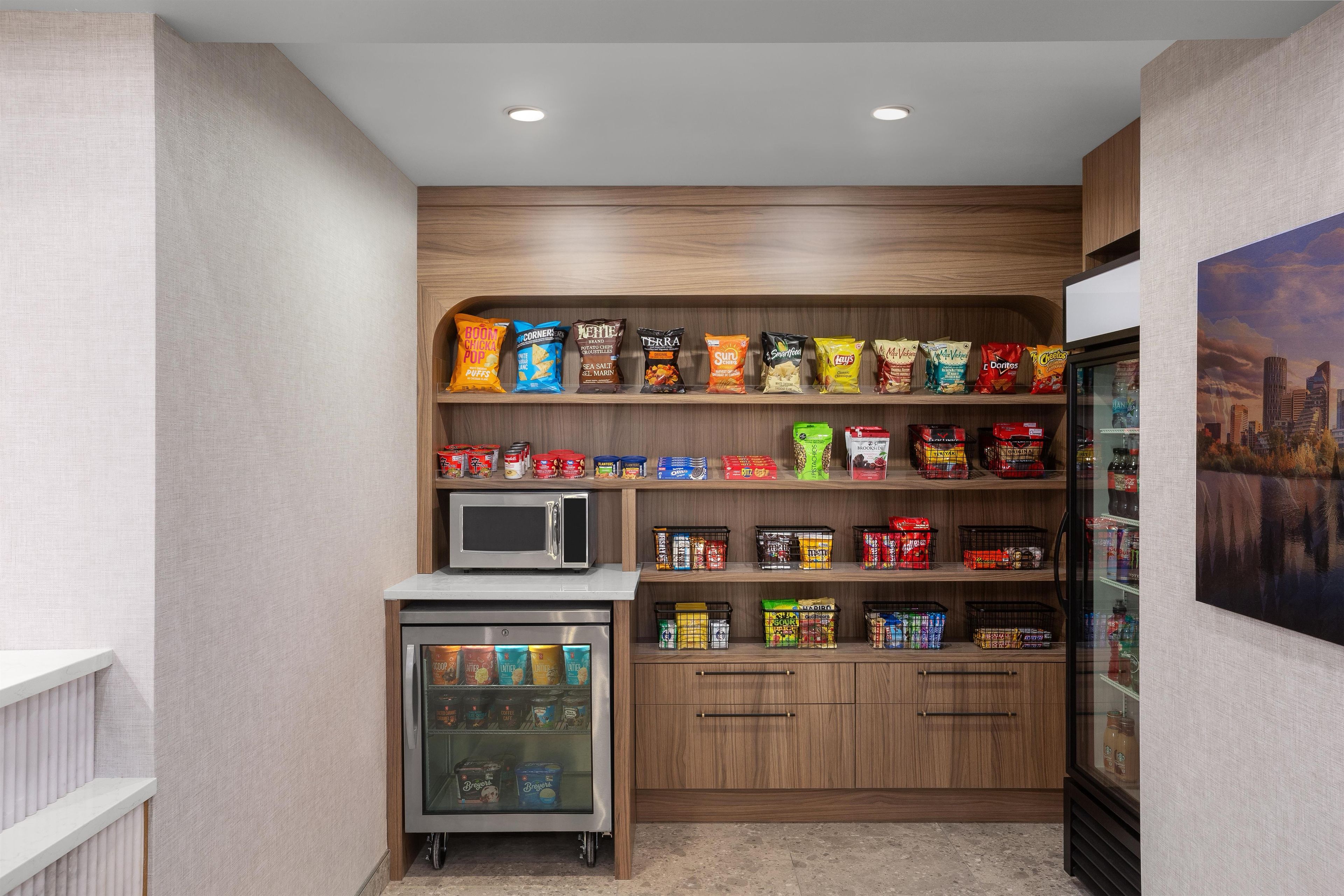 A snack and beverage vending area with a microwave and refrigerated section.