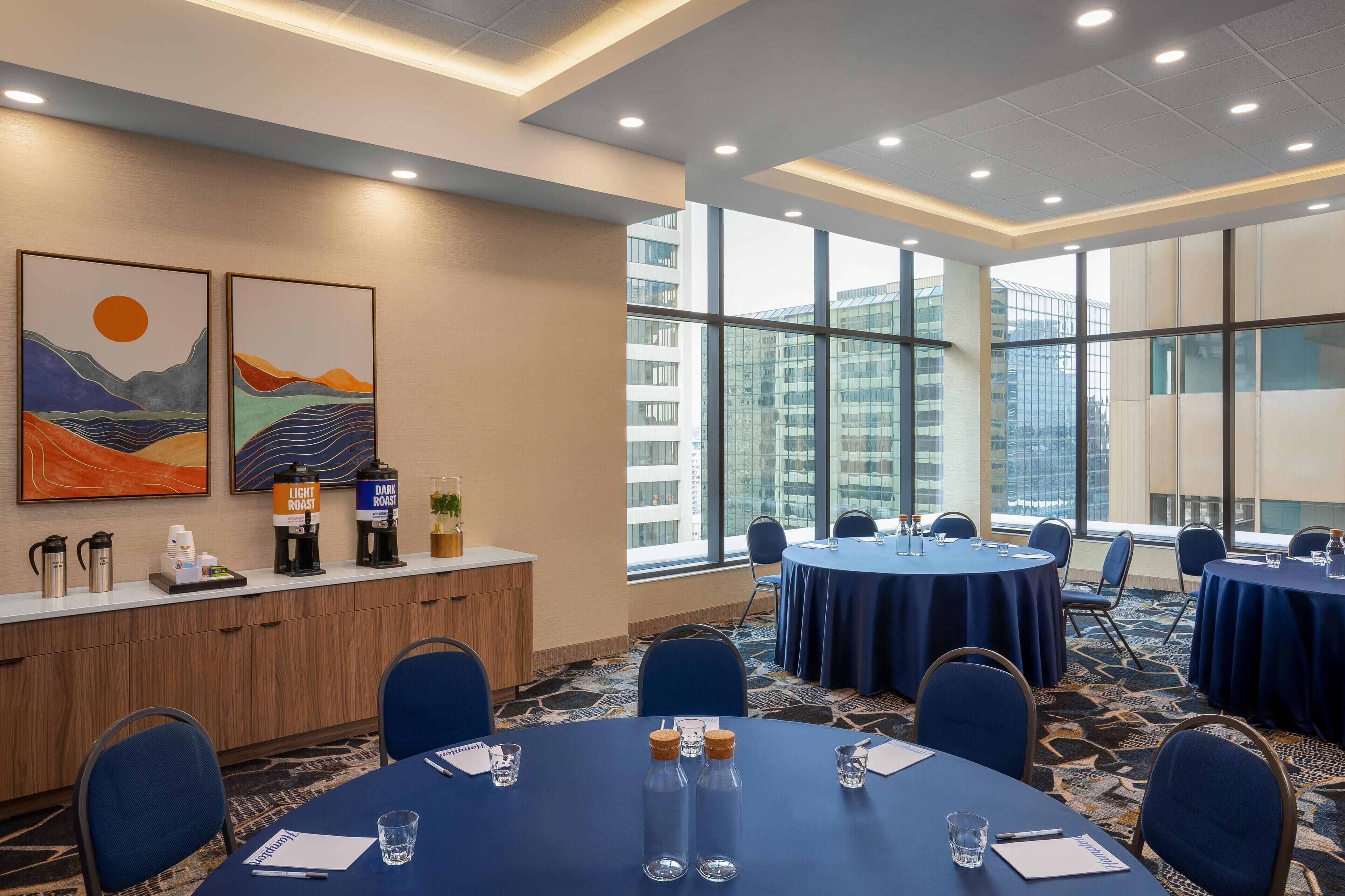 A conference room with round tables, chairs, and a coffee station.