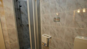 Une salle de bain avec une douche, des toilettes et un porte-serviettes.