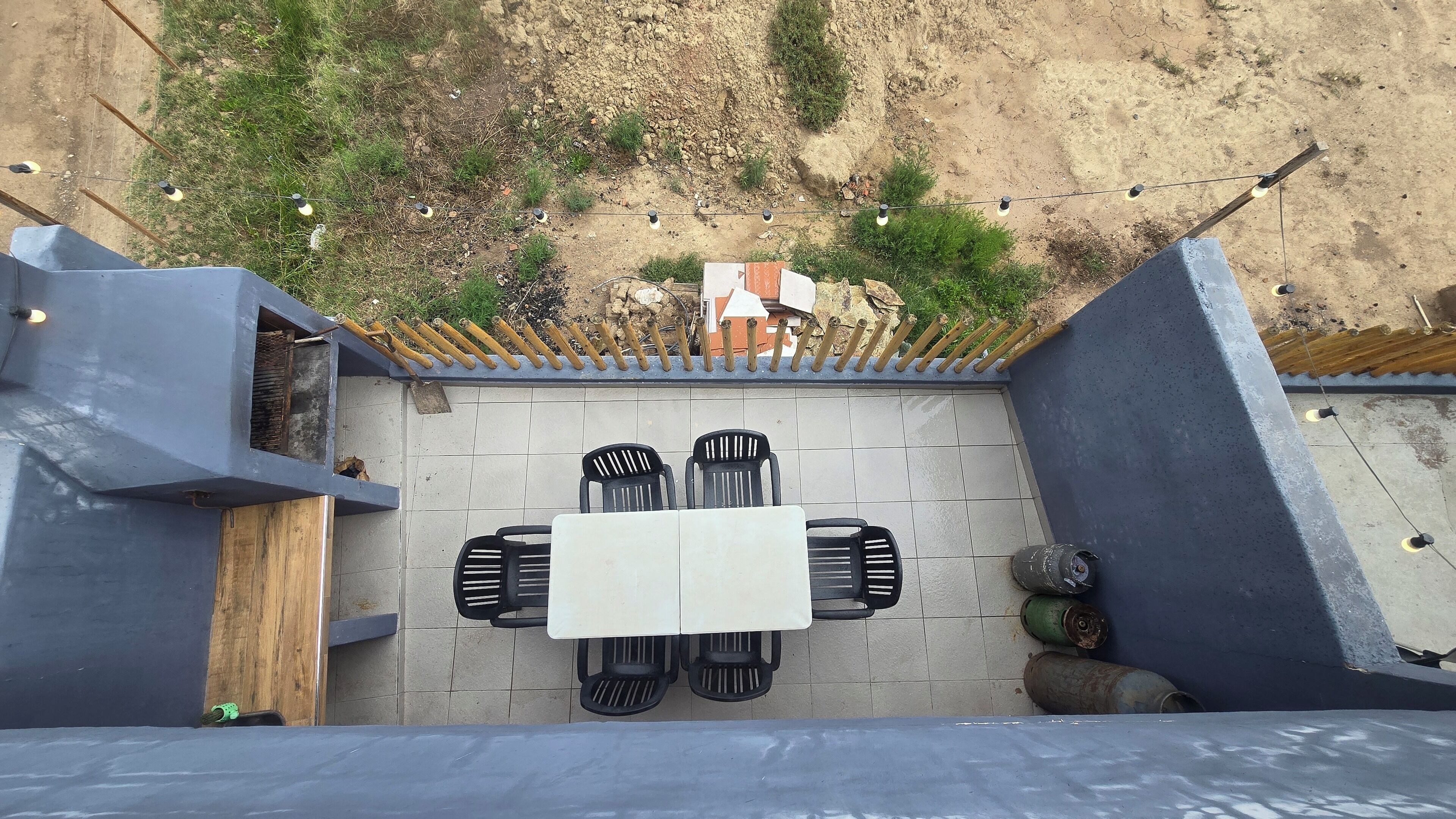 A patio area with a tiled floor, a table with four chairs, and a wooden bench.