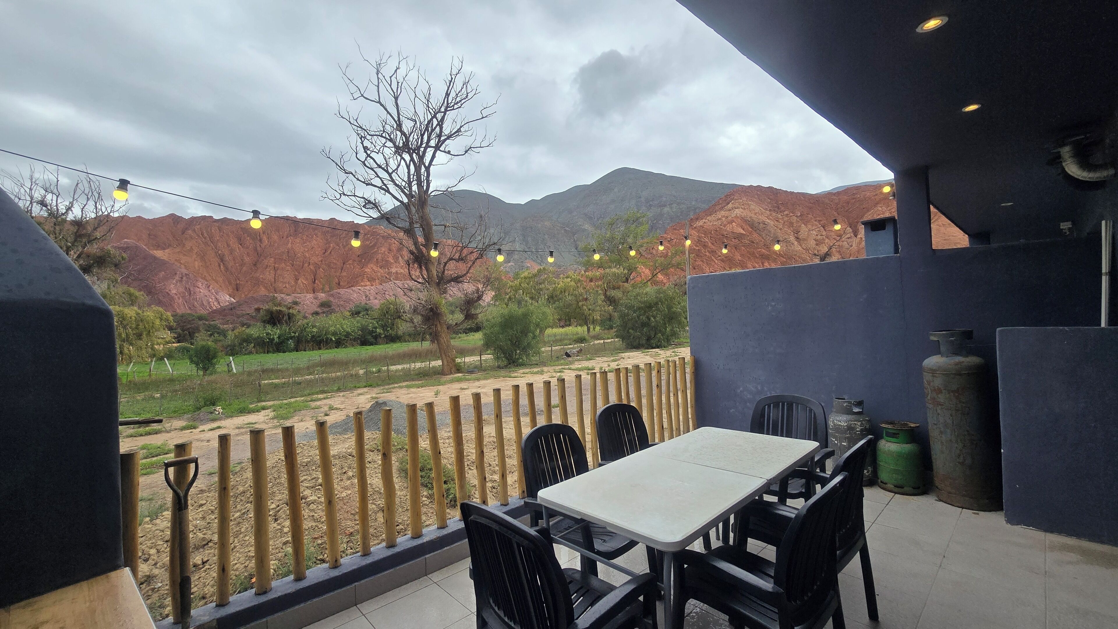 En udendørs terrasse med et bord og stole, med udsigt til et bjergrigt landskab.