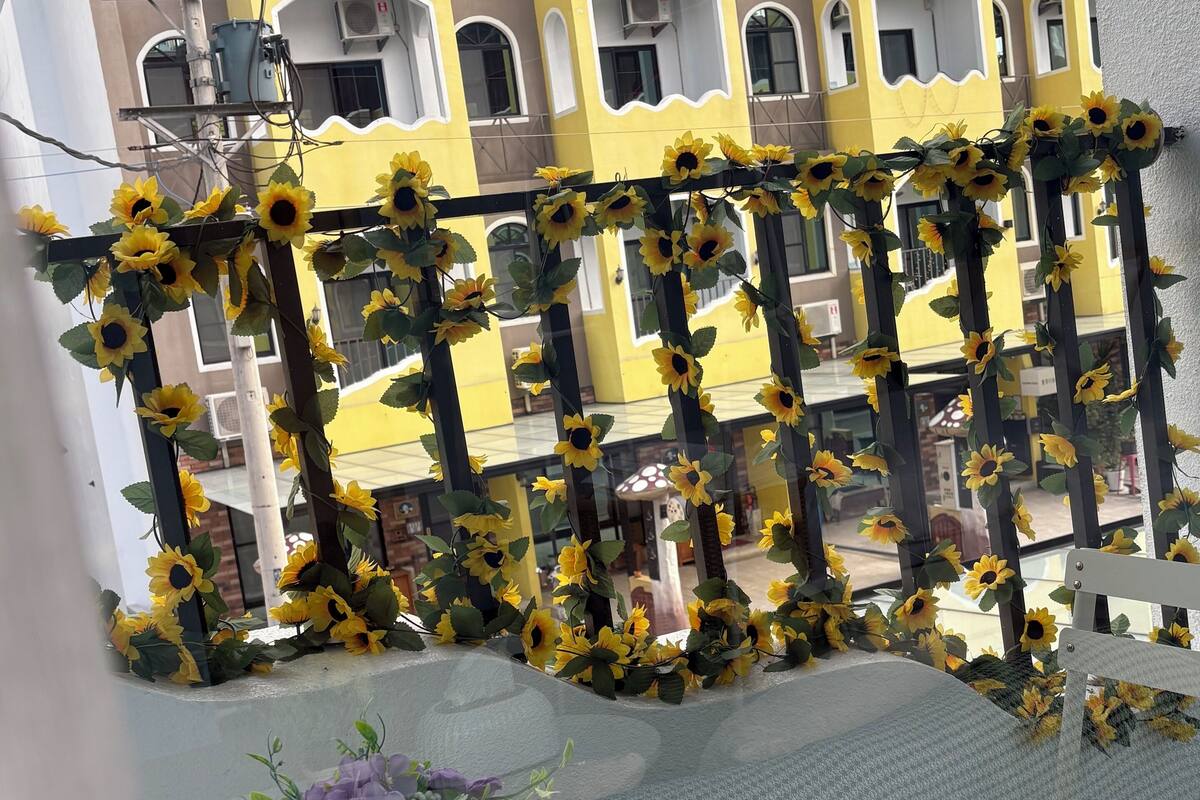 A balcony with a table and chairs, decorated with sunflowers.