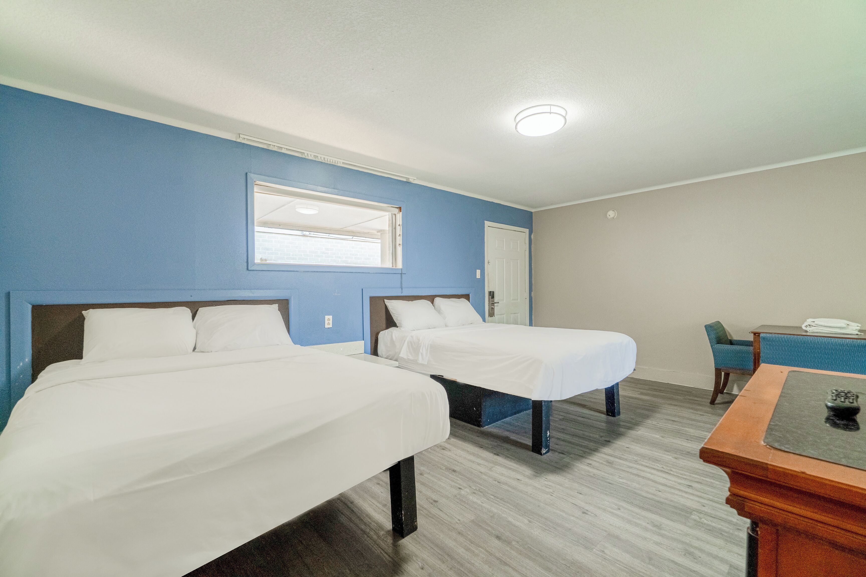 A room with two beds, a desk, and a chair.