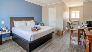 Een slaapkamer met een bed, nachtkastje, stoel, bureau en een televisie.