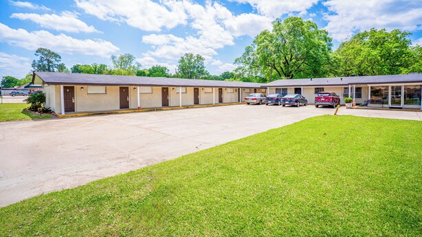 Un motel con diverse camere, un parcheggio e una zona verde.