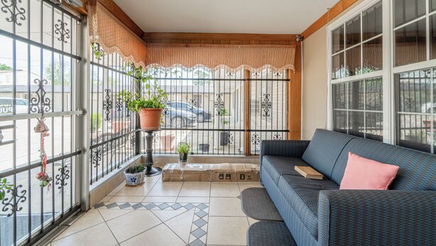 Een balkon met een bank, planten in potten en uitzicht op de straat.