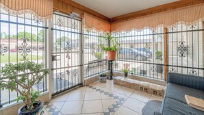 Een balkon met een bloempot, een bank en uitzicht op de straat.