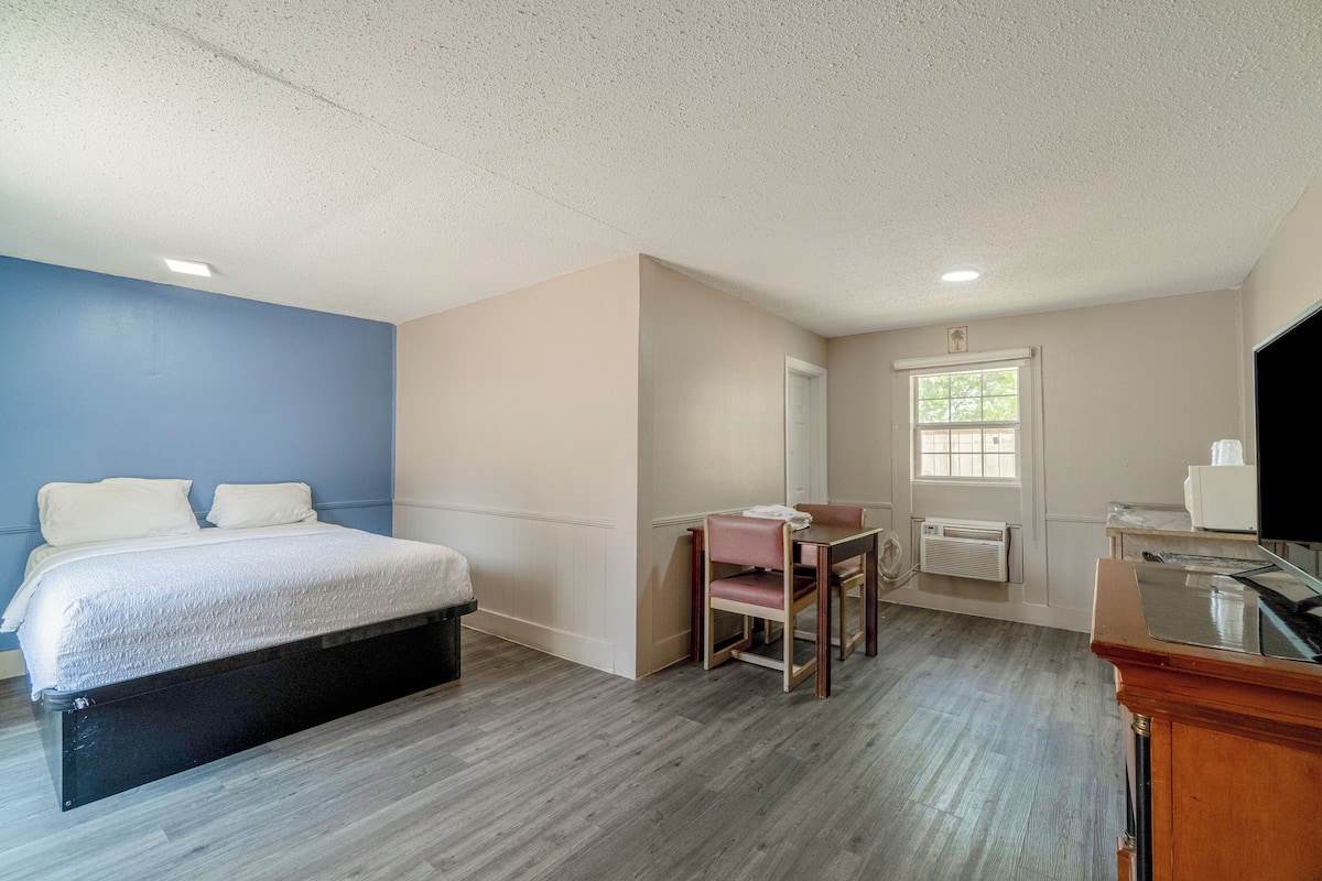 A bedroom with a bed, a desk, and a chair.