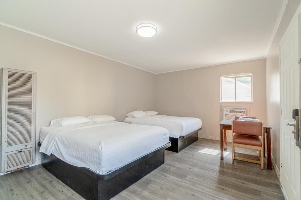 Une chambre avec deux lits, un bureau et une chaise.