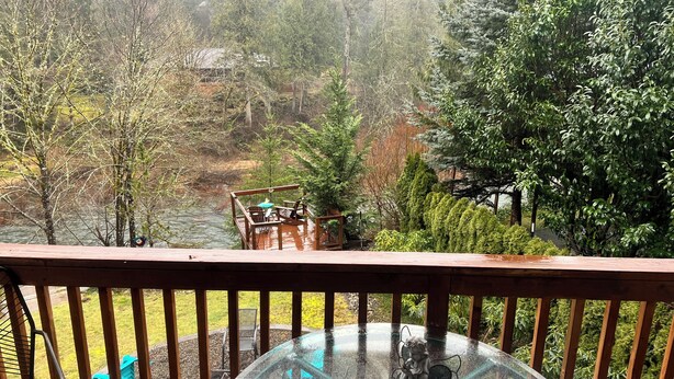 A wooden deck with a glass table and chairs, overlooking a river and trees. - Washougal River Front Apt. Pets OK
Close to Columbia Gorge, close to PDX (Washougal)