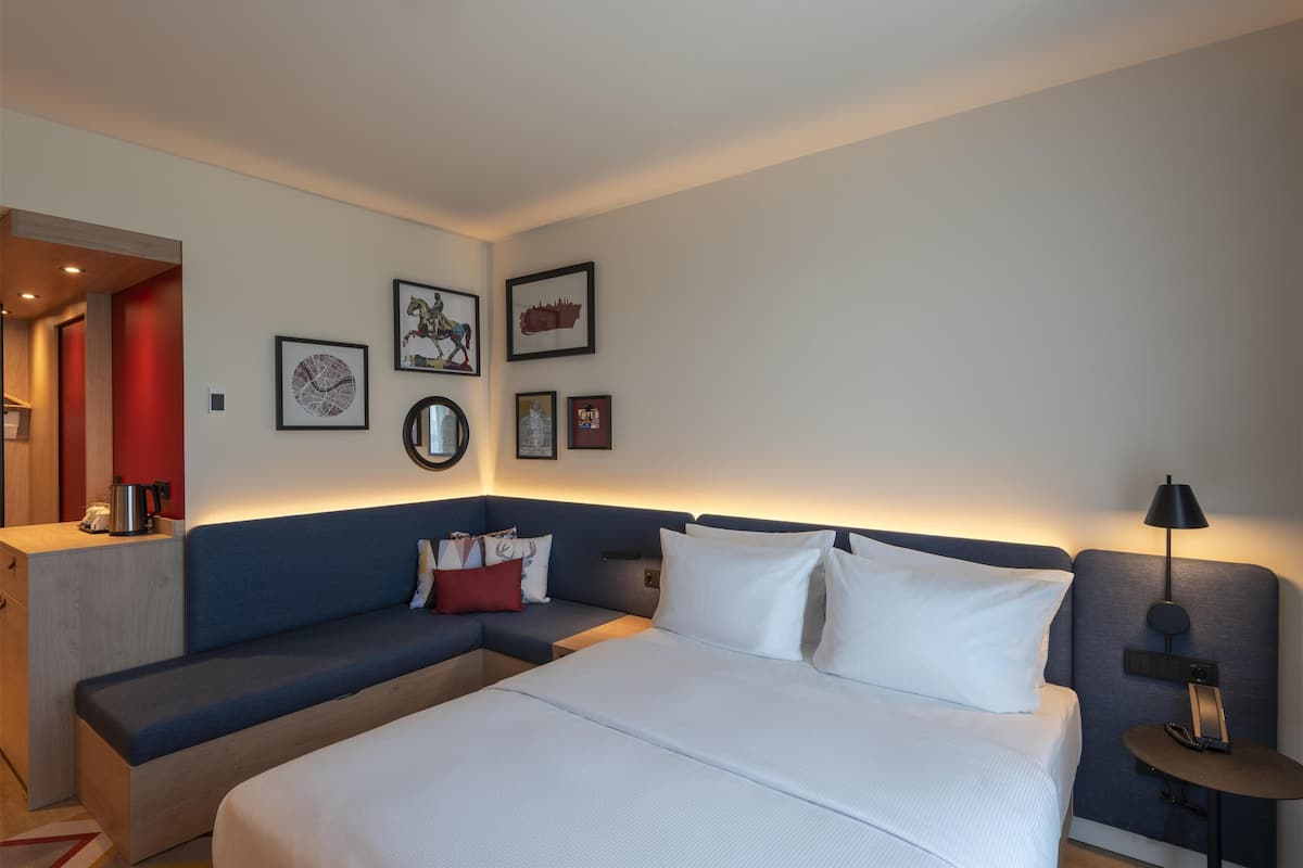 Une chambre d’hôtel moderne avec un grand lit, un canapé, une petite table et un bureau.