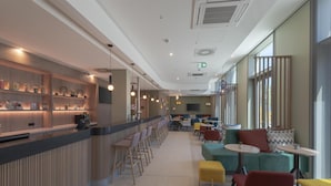 Un espace bar moderne doté d’un comptoir, de sièges et offrant une vue sur l’extérieur.