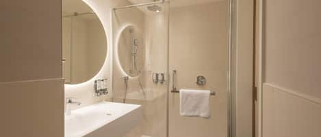 A modern bathroom with a glass-enclosed shower, a large mirror, and a white sink.