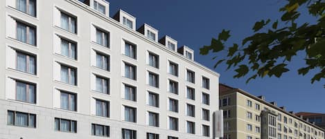 Un hotel moderno con fachada plana, múltiples ventanales y una entrada destacada con un letrero.