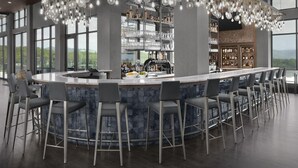 A modern bar area with a curved counter, multiple bar stools, and a large hanging light fixture. - Tempo By Hilton Pigeon Forge (Pigeon Forge)