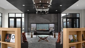 A modern lounge area with a fireplace, bookshelves, and a large window offering a city view. - Tempo By Hilton Pigeon Forge (Pigeon Forge)