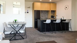 Una cocina compacta con una isla central, un área de comedor con una mesa y sillas, y una pequeña zona de estar con sofá.