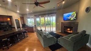 A modern living room with a fireplace, a large TV, and a bar area.