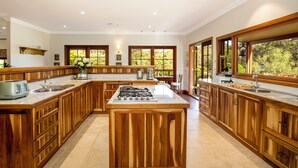 Una cocina amplia con armarios de madera, una isla central y ventanas grandes que ofrecen vistas al exterior.
