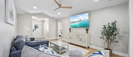 A modern living room with a grey sofa, a coffee table, and a TV mounted on the wall.
