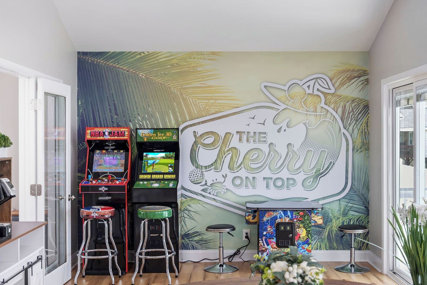 Ein Raum mit Spielautomaten, einer Wandmalerei mit Kirschmotiven und einer Bar.