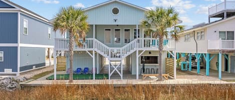 A coastal house with a central porch, a staircase, and a pool area.