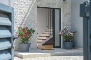 Stylish entrance with a minimalist design, featuring a set of stairs and lush greenery.