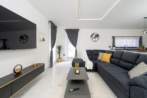 Relax in this stylish living room with a sofa, coffee table, flat-screen TV, and a touch of greenery.