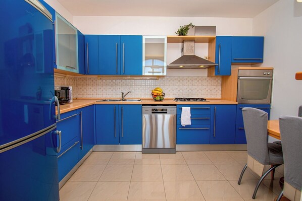 Enjoy cooking in this well-lit kitchen with an oven, stainless steel appliances, and a dining area.