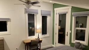 Ett sovrum med en säng, ett skrivbord med en stol, en lampa och en takfläkt.