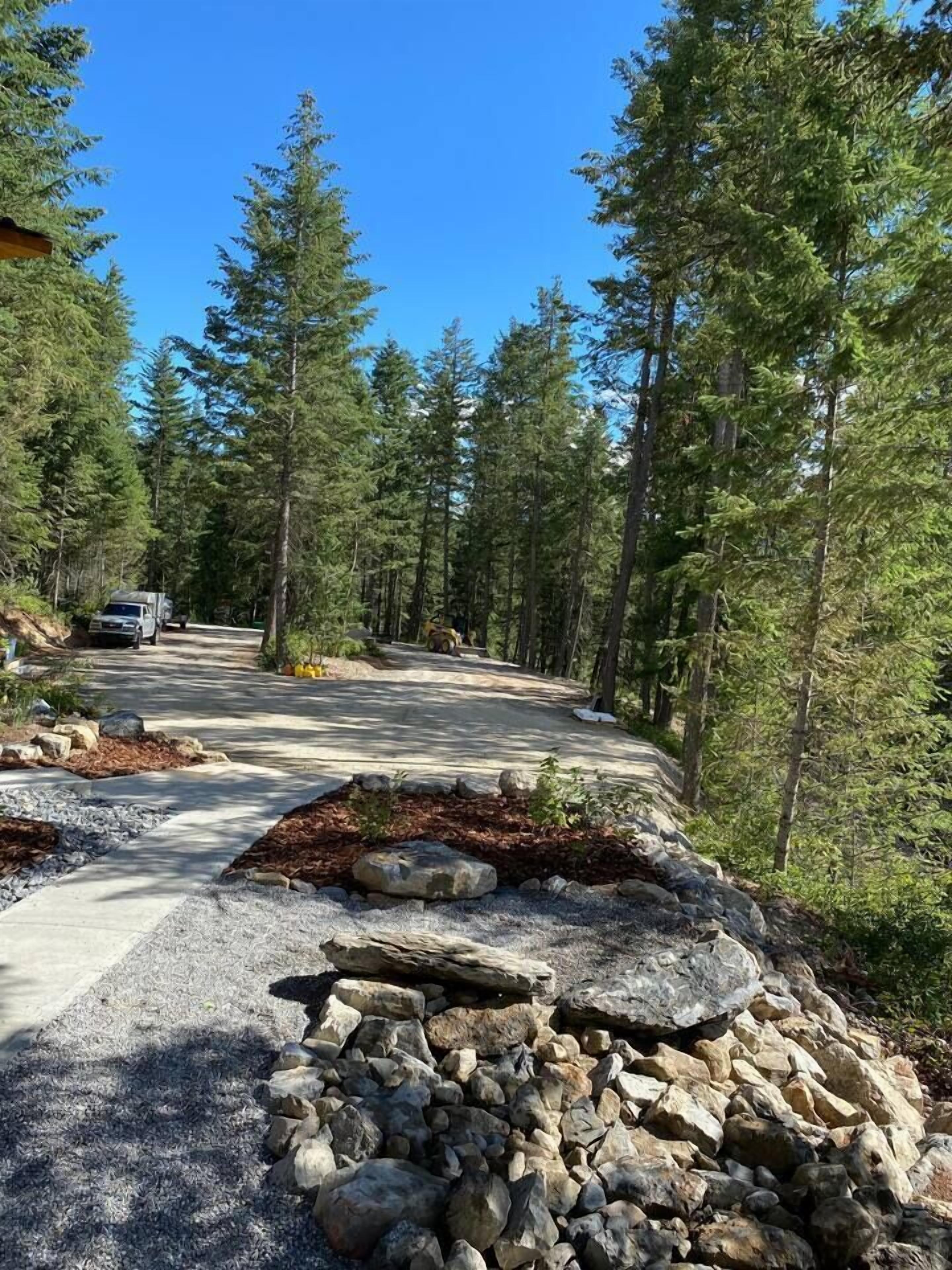 A paved road winding through a forested area with a truck parked on the side.