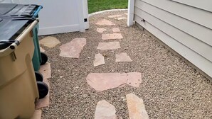 A gravel pathway leading to a white door with a mailbox.