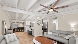 A modern living room with a grey sofa, a wooden coffee table, and a ceiling fan.