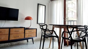 Un salon moderne doté d’un téléviseur à écran plat, d’un meuble en bois et d’une table à manger avec des chaises.