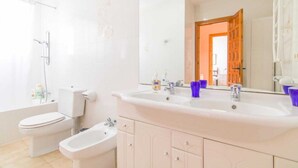 A bathroom with a toilet, bidet, and a sink with a mirror. - Bungalow - CalpePark (Calpe)