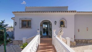 Um edifício branco com telhado em azulejos, entrada central e guarda-corpo branco.