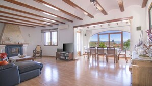 Uma sala de estar ampla com lareira, televisão e área de jantar com vista.
