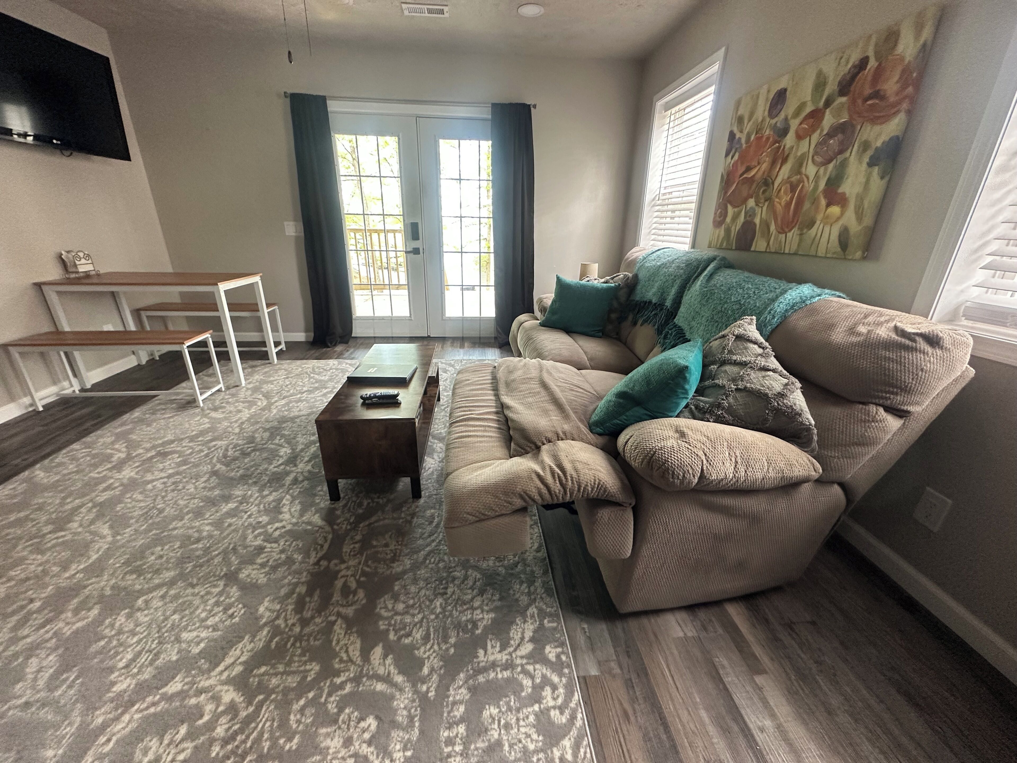A living room with a sofa, coffee table, and a TV mounted on the wall.