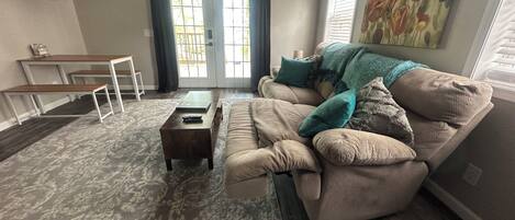 A living room with a sofa, coffee table, and a TV mounted on the wall.