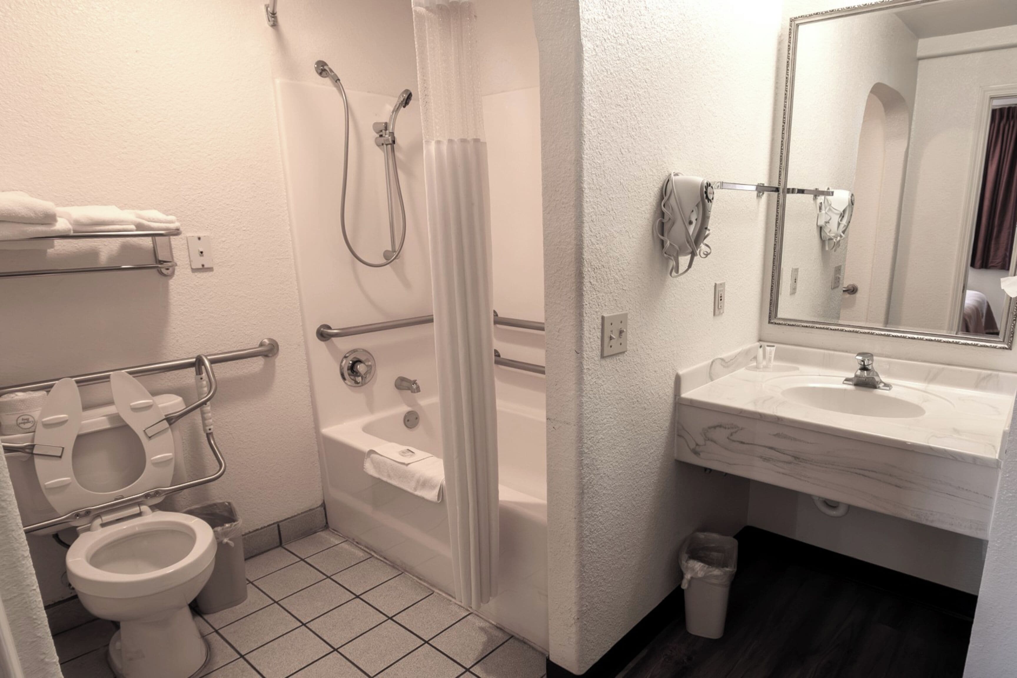 A bathroom with a toilet, shower, and sink.