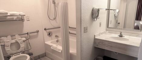 A bathroom with a toilet, shower, and sink.