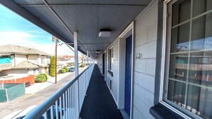 A corridor with a black carpet, white railings, and a blue door. - Hotel Inn Pendleton I-84 (Pendleton)