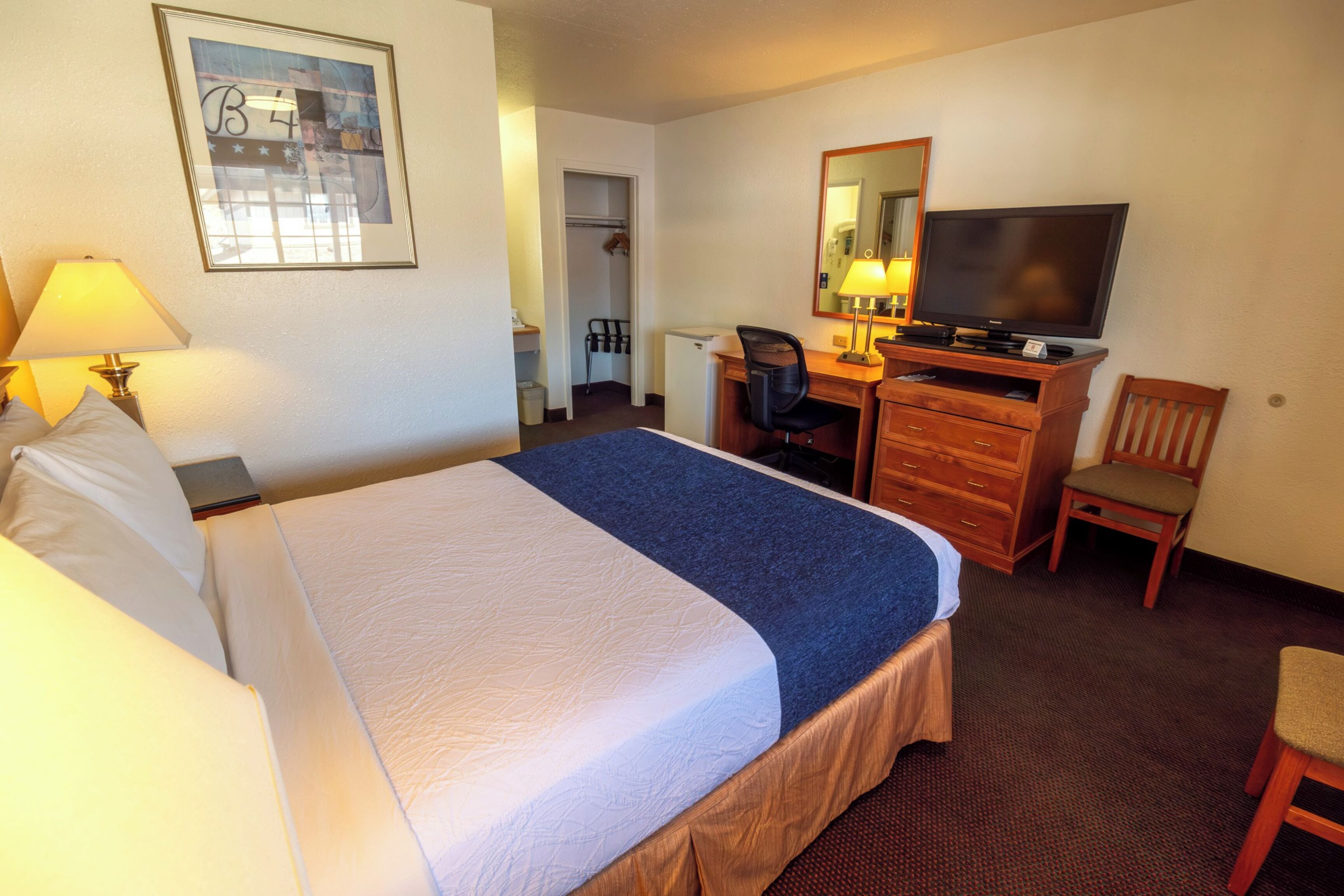 A hotel room with a bed, a desk, a television, and a chair.