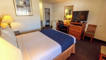 A hotel room with a bed, a desk, a television, and a chair.