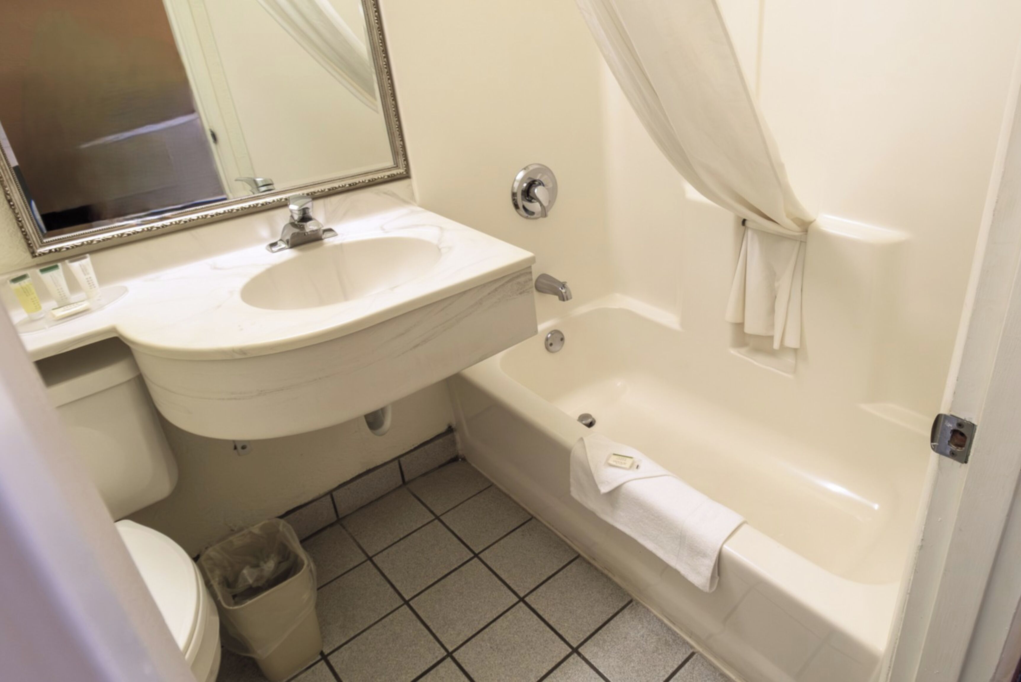 A bathroom with a sink, mirror, toilet, and bathtub.