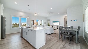 A modern kitchen with white cabinetry, a central island, and pendant lighting. - PRIVATE HOME WITH BEACH ACCESS AND POOLS! (Gulf Shores)