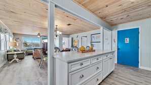 A spacious living area with a large white cabinet, wooden ceiling, and a bright blue door. - COZY LIVING ON THE BEACH! (Gulf Shores)