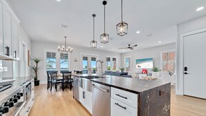 A modern kitchen with stainless steel appliances, a marble island, and pendant lighting. - ULTIMATE LUXURY ON THE WATER! PRIVATE POOL AND HOT TUB! (Gulf Shores)