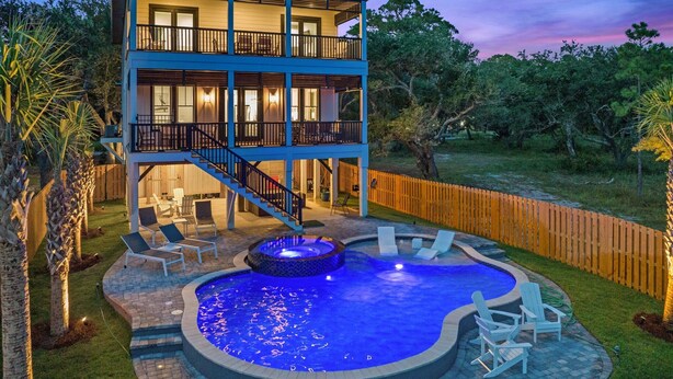 A two-story house with a swimming pool, outdoor seating, and a wooden fence. - ULTIMATE LUXURY ON THE WATER! PRIVATE POOL AND HOT TUB! (Gulf Shores)